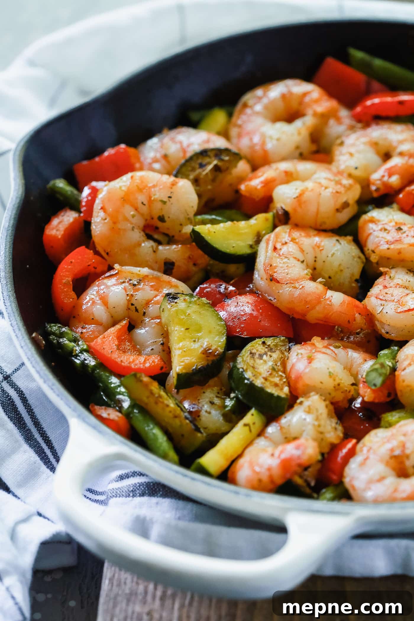 Keto Dinner Recipes: Low-Carb Ideas for Weeknights 22 Overhead view of a cast iron with shrimp, bell peppers, zucchini, and asparagus.