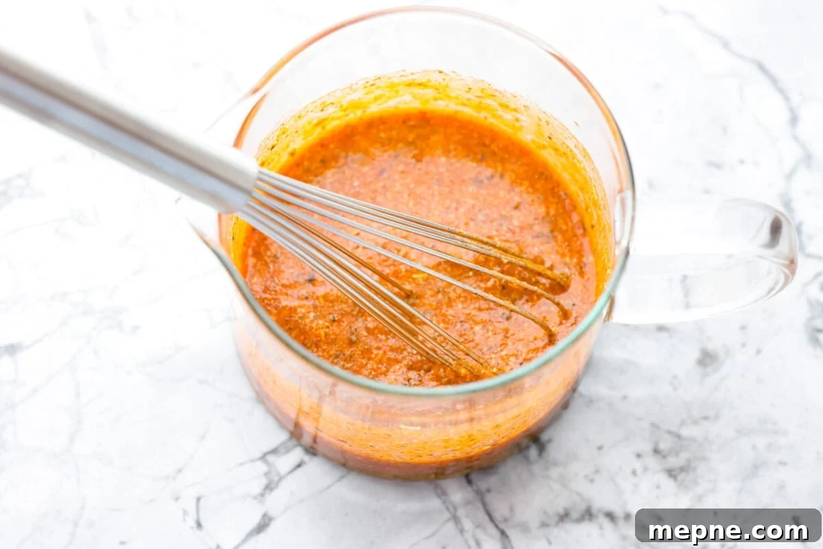 Dressing ingredients whisked together in a pouring container.