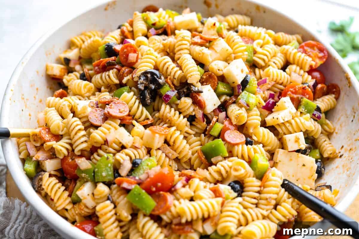Pasta, vegetables, meat, cheese, and dressing mixed together.