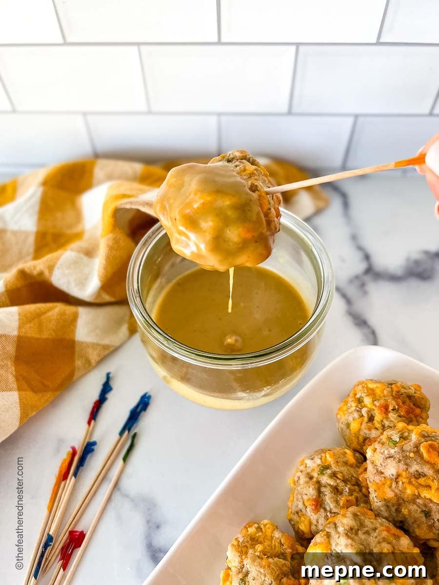 Turkey Sausage Balls Recipe 9 Turkey sausage balls on a platter, and one on a toothpick, being dipped into mustard sauce.