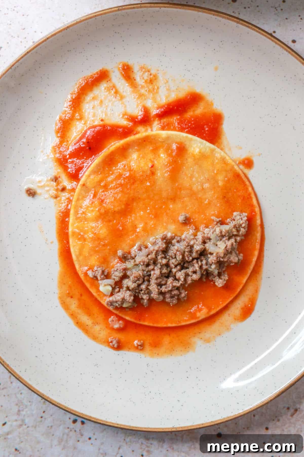 Corn tortilla with tomato sauce and ground beef filling