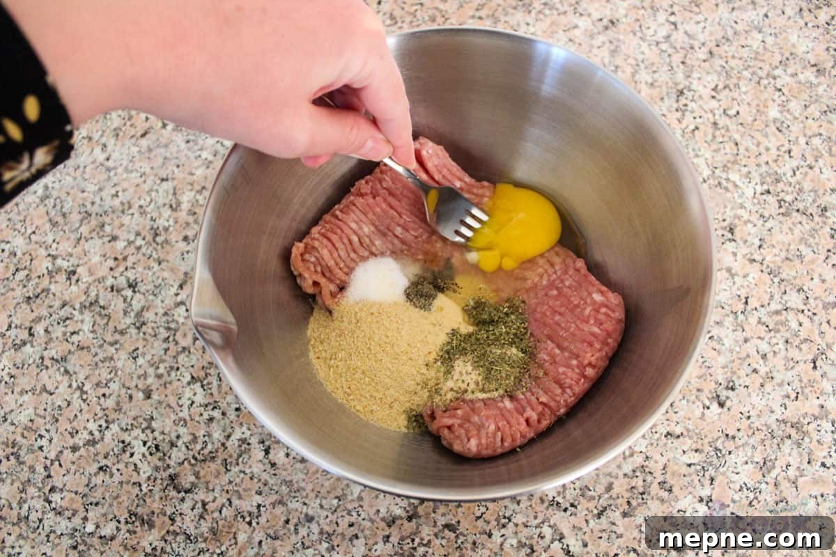 Oven Baked Pork Meatballs with Italian Seasoning 4 All the meatball ingredients in a medium bowl, with a fork breaking the egg yolk as mixing begins.