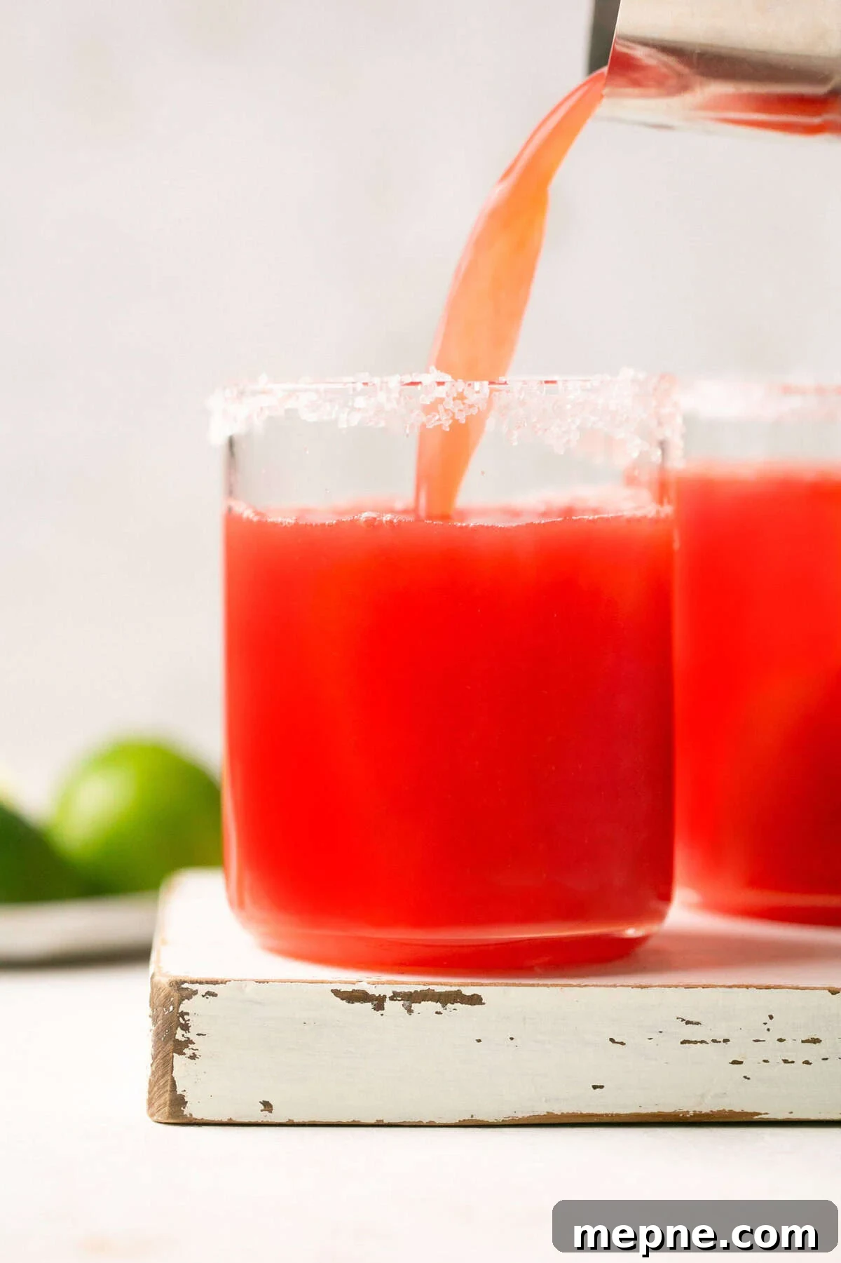 1800 Tequila Watermelon Margarita Recipe 5 a shaker pouring watermelon margarita mix into a glass