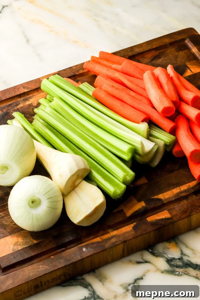 Romanian Chicken Soup (Ciorbă de pui) Recipe 3 vegetables peeled and sliced in half on a cutting board