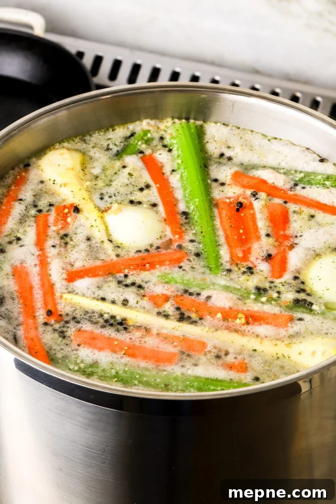 Romanian Chicken Soup (Ciorbă de pui) Recipe 7 foam collecting on top of soup in a large pot, vegetables rising