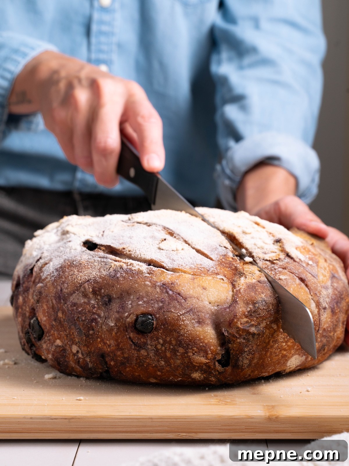 Homemade Blueberry Sourdough Bread Recipe 12 Slicing a homemade sourdough boule filled with dried blueberries