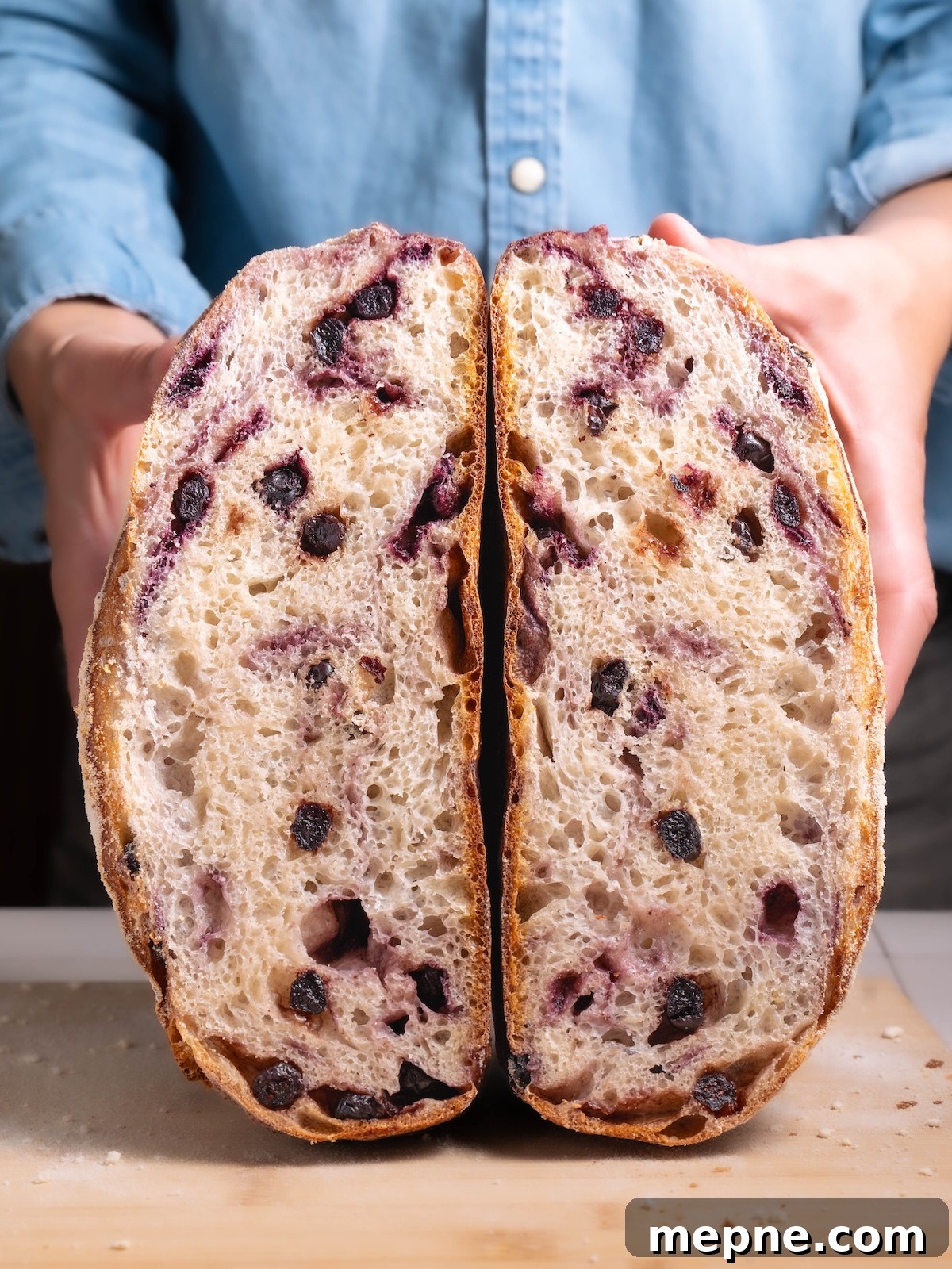 Homemade Blueberry Sourdough Bread Recipe 3 A loaf of blueberry sourdough bread sliced in half to show interior