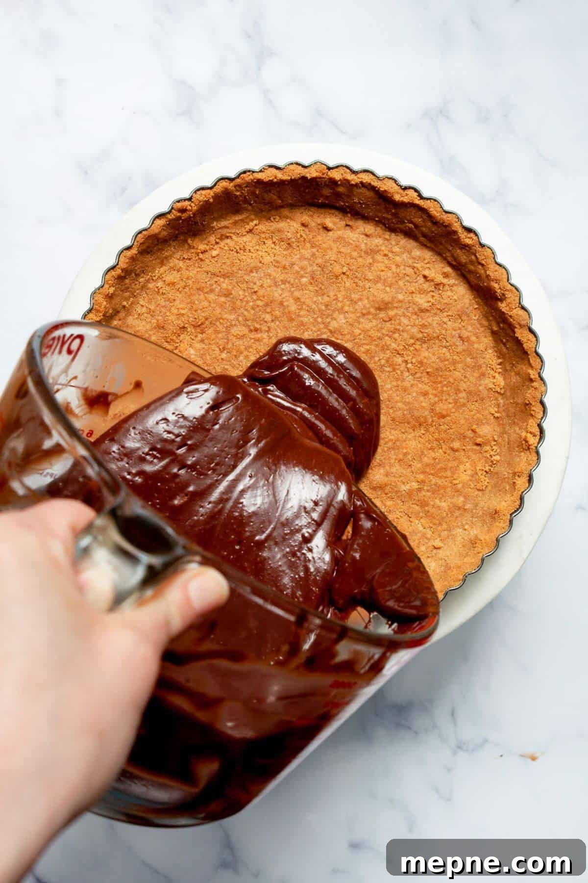 Dark Chocolate Raspberry Tart Recipe 7 Silky dark chocolate ganache being poured into a pre-baked graham cracker tart crust.