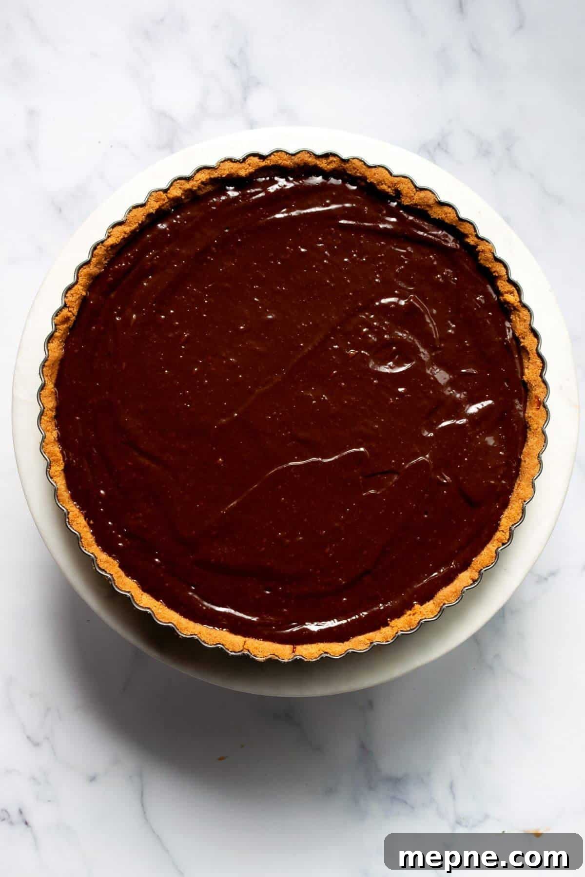 Dark Chocolate Raspberry Tart Recipe 8 Smooth dark chocolate ganache filling set in a graham cracker tart crust, ready for topping.