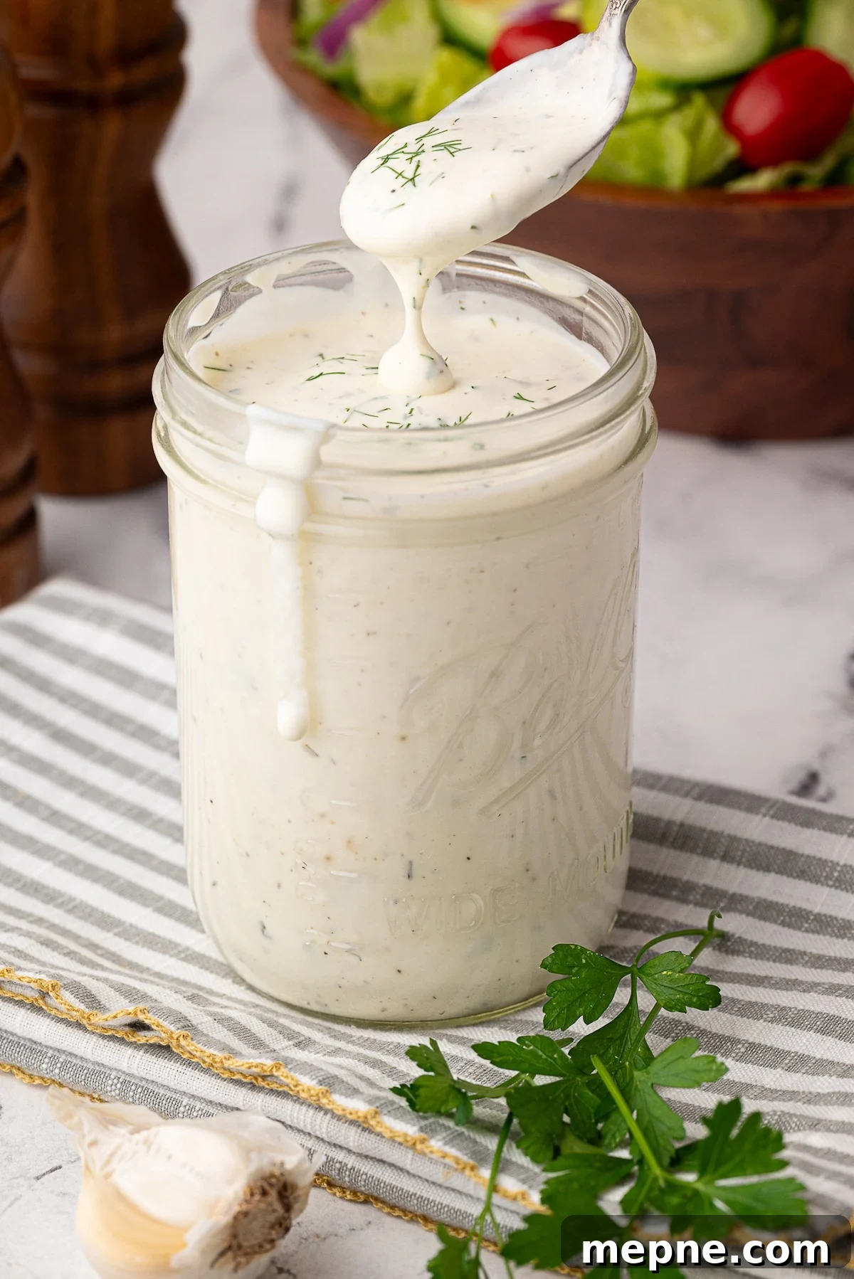 How to Make Creamy Buttermilk Ranch Dressing 2 prepared ranch in jar garnished with herbs and house salad