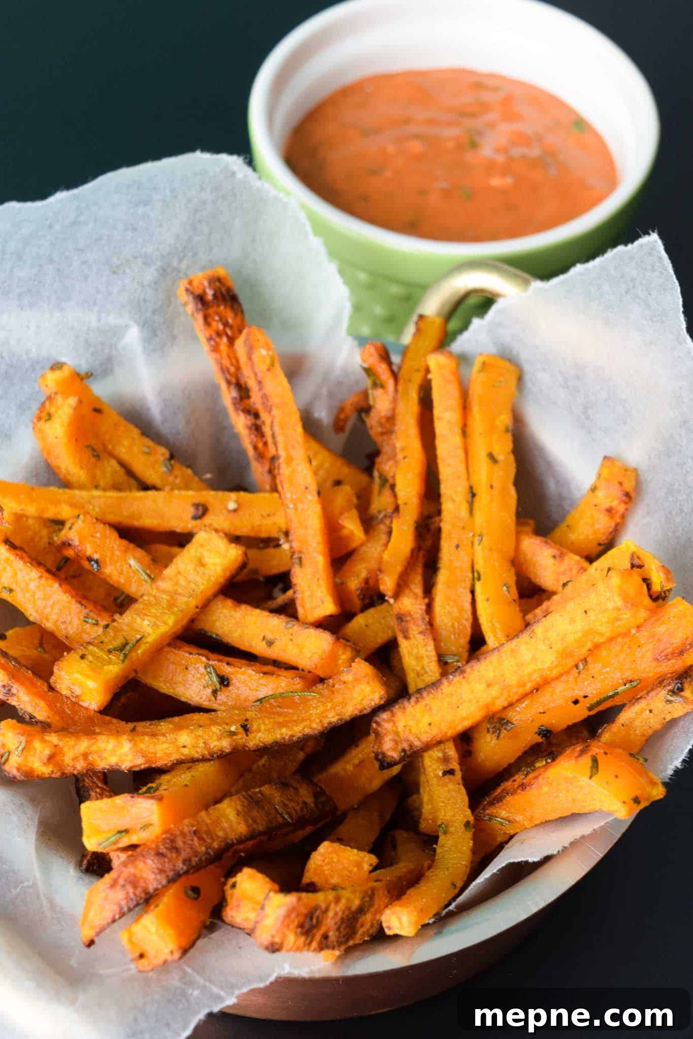 Butternut Squash Fries in waxed paper lined bowl with magic sauce in green bowl behind