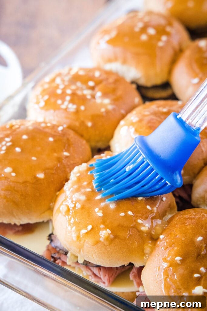 French Dip Sliders Recipe: Mini Beef Sandwiches with Au Jus 3 brushing butter on french dip sliders