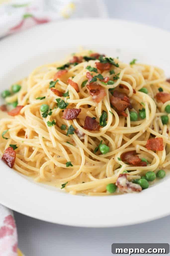 Classic Spaghetti Carbonara with Pancetta and Pecorino 2 A plate full of easy Spaghetti Carbonara topped with bacon and peas.