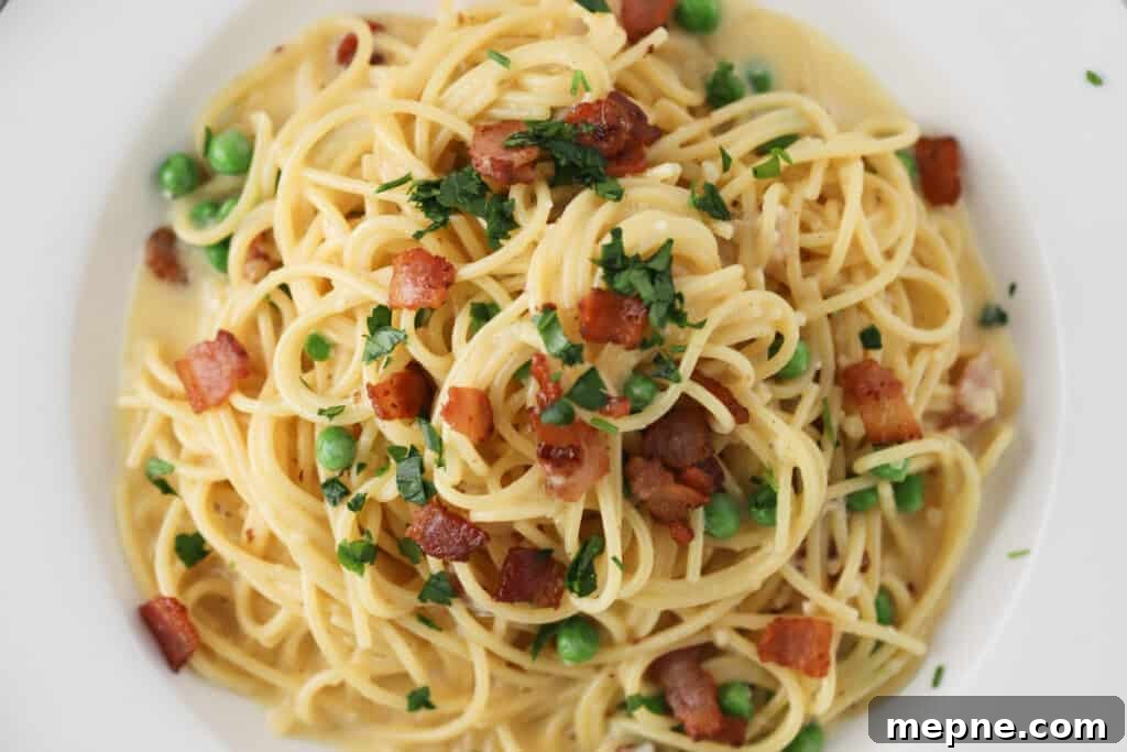 Classic Spaghetti Carbonara with Pancetta and Pecorino 5 A bowl full of Spaghetti alla Carbonara topped with parsley, bacon, and peas.