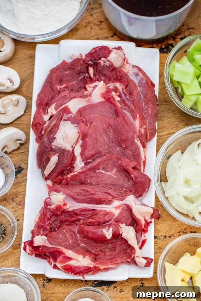 Tender Slow Cooker Swiss Steak Recipe 4 Overhead shot of slow cooker Swiss steak ingredients arranged on a wooden table.
