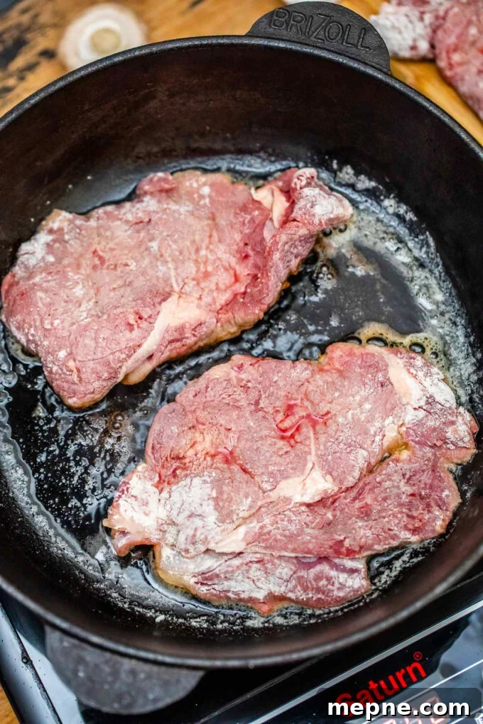 Tender Slow Cooker Swiss Steak Recipe 6 Searing round steaks in a cast iron skillet.