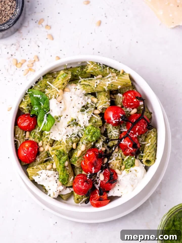 Pesto Rigatoni with Burst Cherry Tomatoes and Burrata 2 white bowl with rigatoni pasta covered in pesto topped with burrata cheese and burst tomatoes