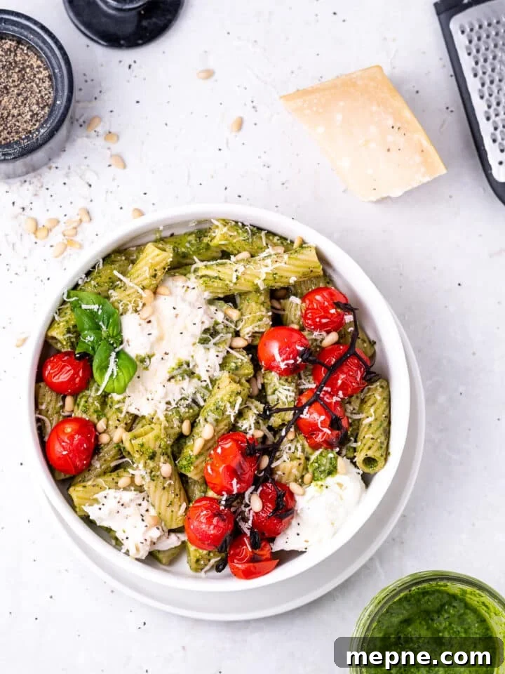 Pesto Rigatoni with Burst Cherry Tomatoes and Burrata 11 white bowl with the featured recipe, a block of parmesan cheese and microplane grater