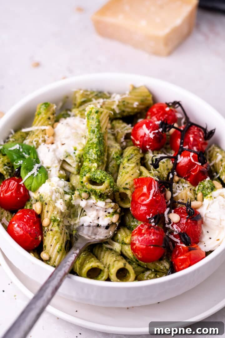 Pesto Rigatoni with Burst Cherry Tomatoes and Burrata 12 fork with a bite of pesto pasta on it
