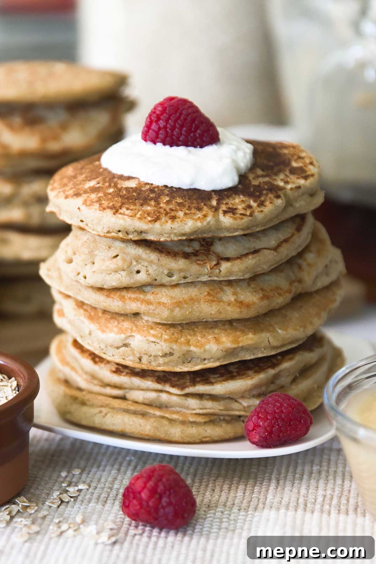 Fluffy Gluten-Free Oat Flour Pancake Recipe 3 Stack of oat flour pancakes on a plate with raspberries.