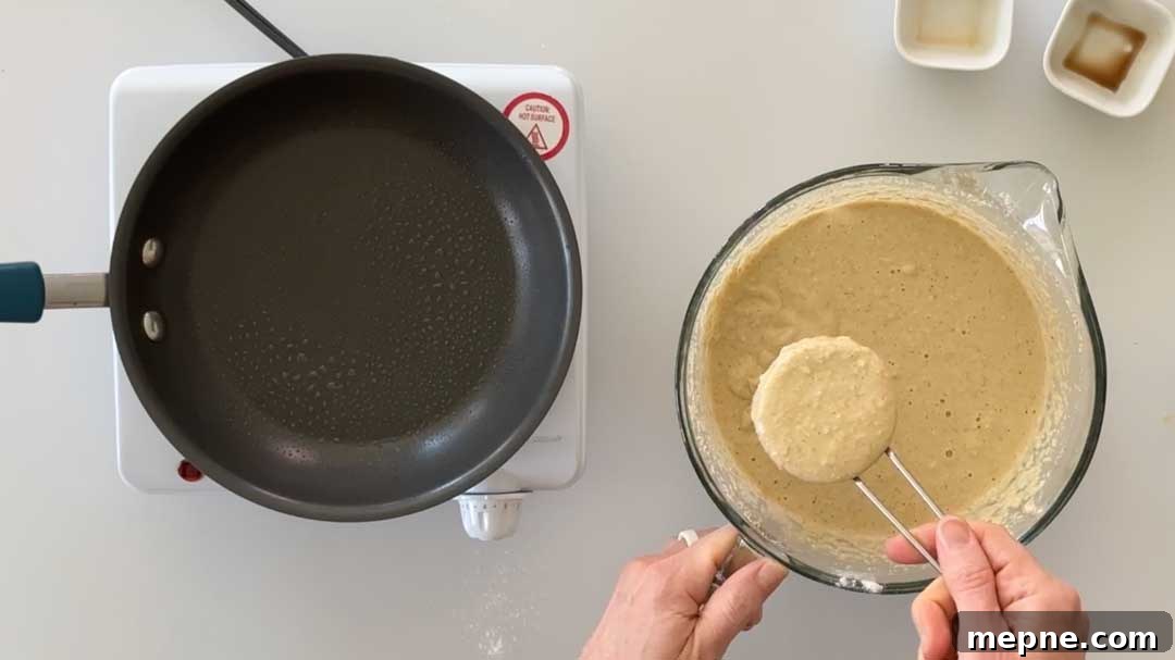 Fluffy Gluten-Free Oat Flour Pancake Recipe 6 Pouring 1/4 a cup of pancake batter into a skillet.
