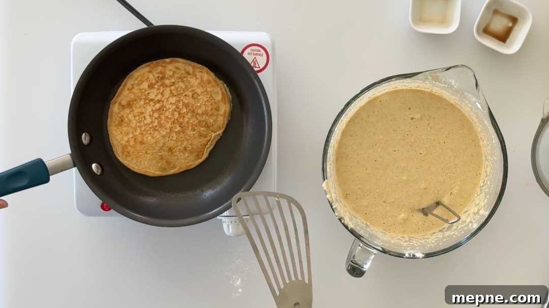 Fluffy Gluten-Free Oat Flour Pancake Recipe 7 Flipping over a pancake in a skillet.