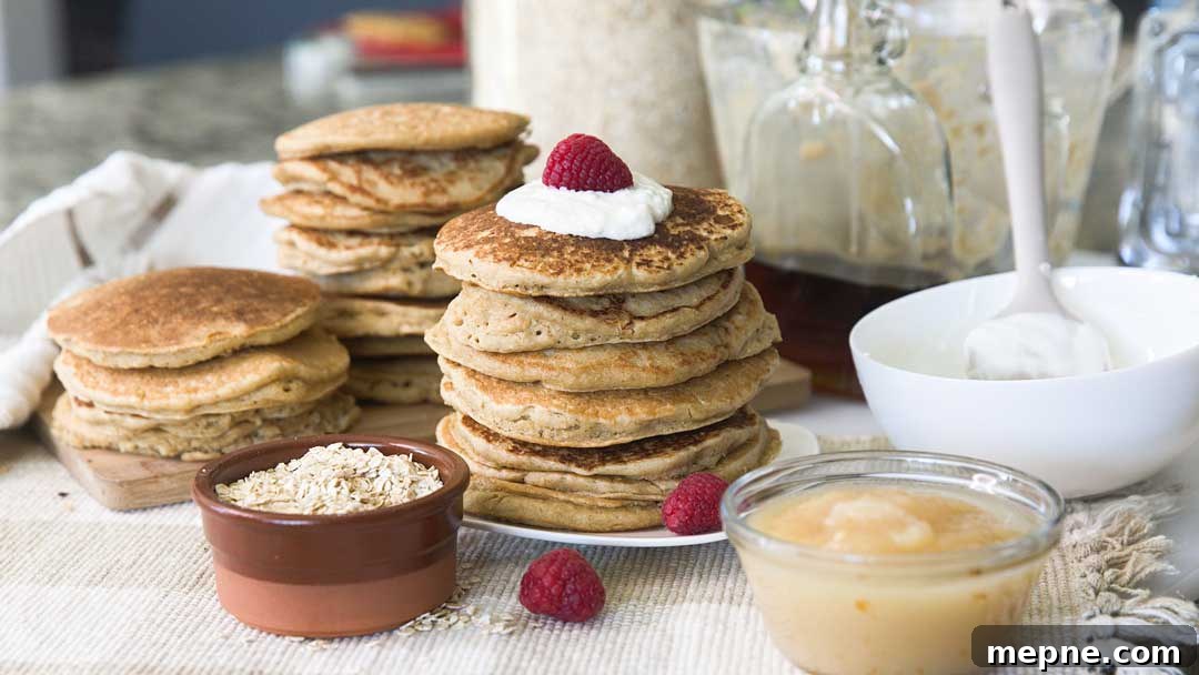 Fluffy Gluten-Free Oat Flour Pancake Recipe 8 A stack of gluten-free oat flour pancakes with cream and raspberries on top.