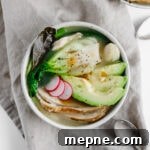 A bowl of asian-inspired leftover turkey soup next to a spoon.