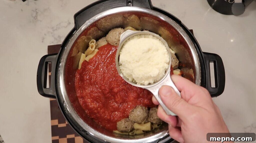 Instant Pot Meatballs with Marinara Pasta 11 Adding grated Parmesan cheese to pot