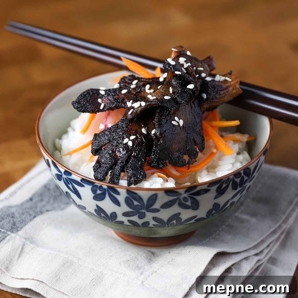 Crispy Chinese Fried Oyster Mushrooms with Vegan Char Siu Recipe 9 Photo of a pretty bowl filled with sushi rice, pickled salad and Char Siu mushrooms, set on a napkin with chop sticks resting.