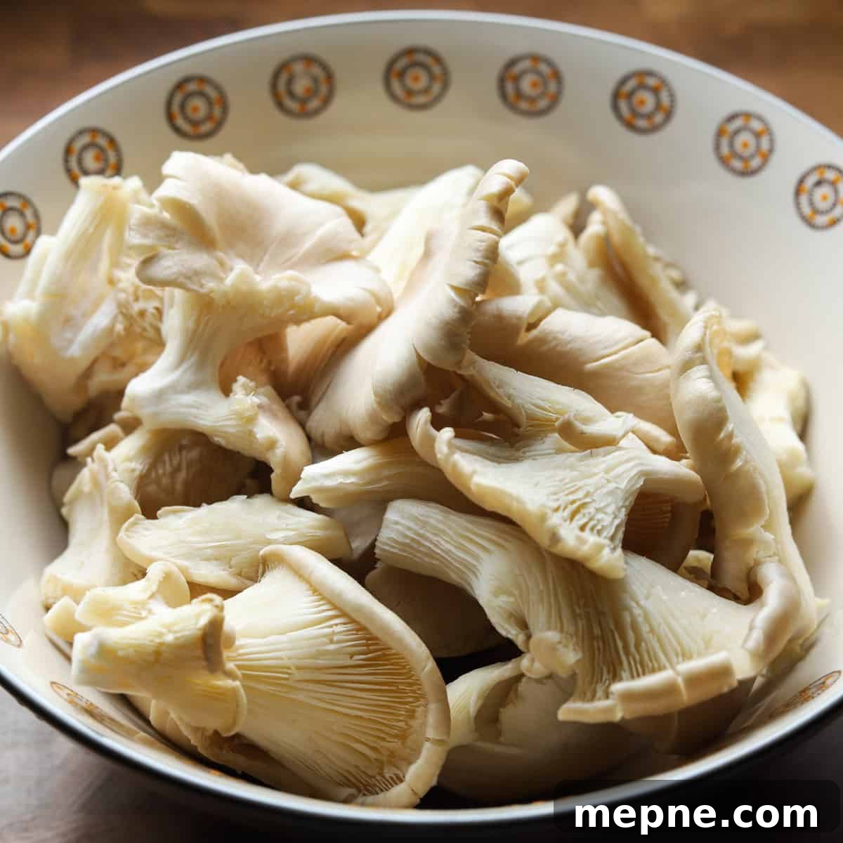 Crispy Chinese Fried Oyster Mushrooms with Vegan Char Siu Recipe 4 Photo showing a bowl of raw pearl oyster mushrooms on a wooden tabletop.