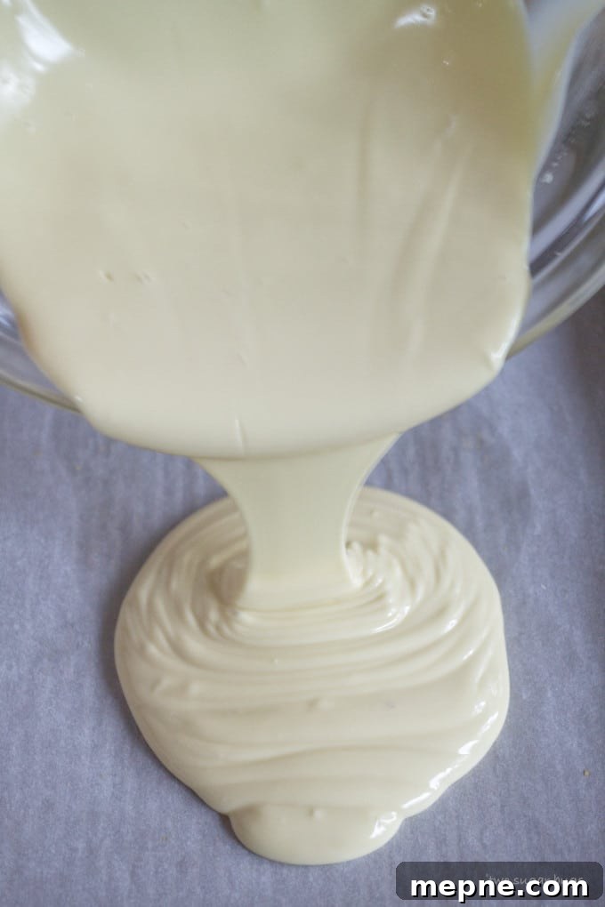 Homemade Cookie Butter White Chocolate Bark Recipe 8 melted white chocolate being poured onto a baking pan