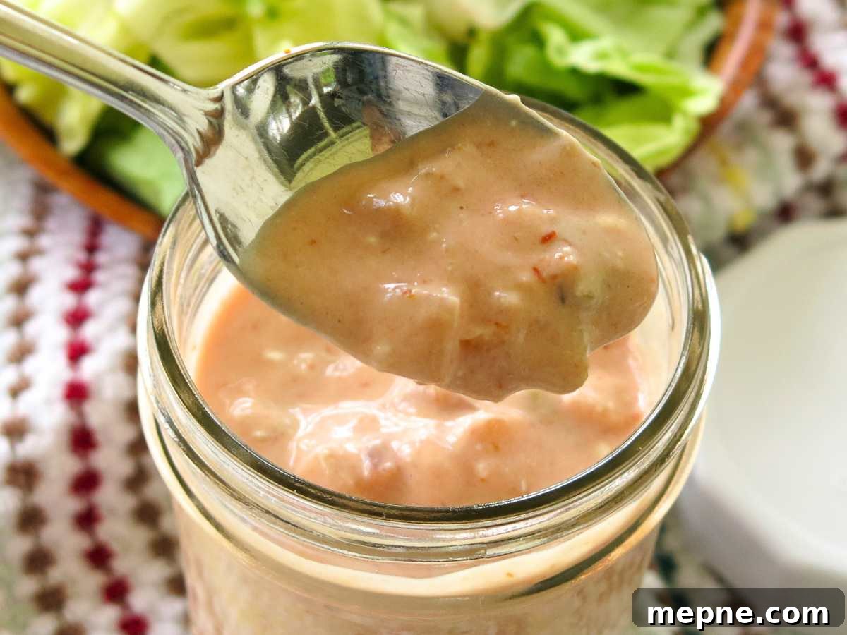 Spoon lifting salsa yogurt taco salad dressing out of a jar.