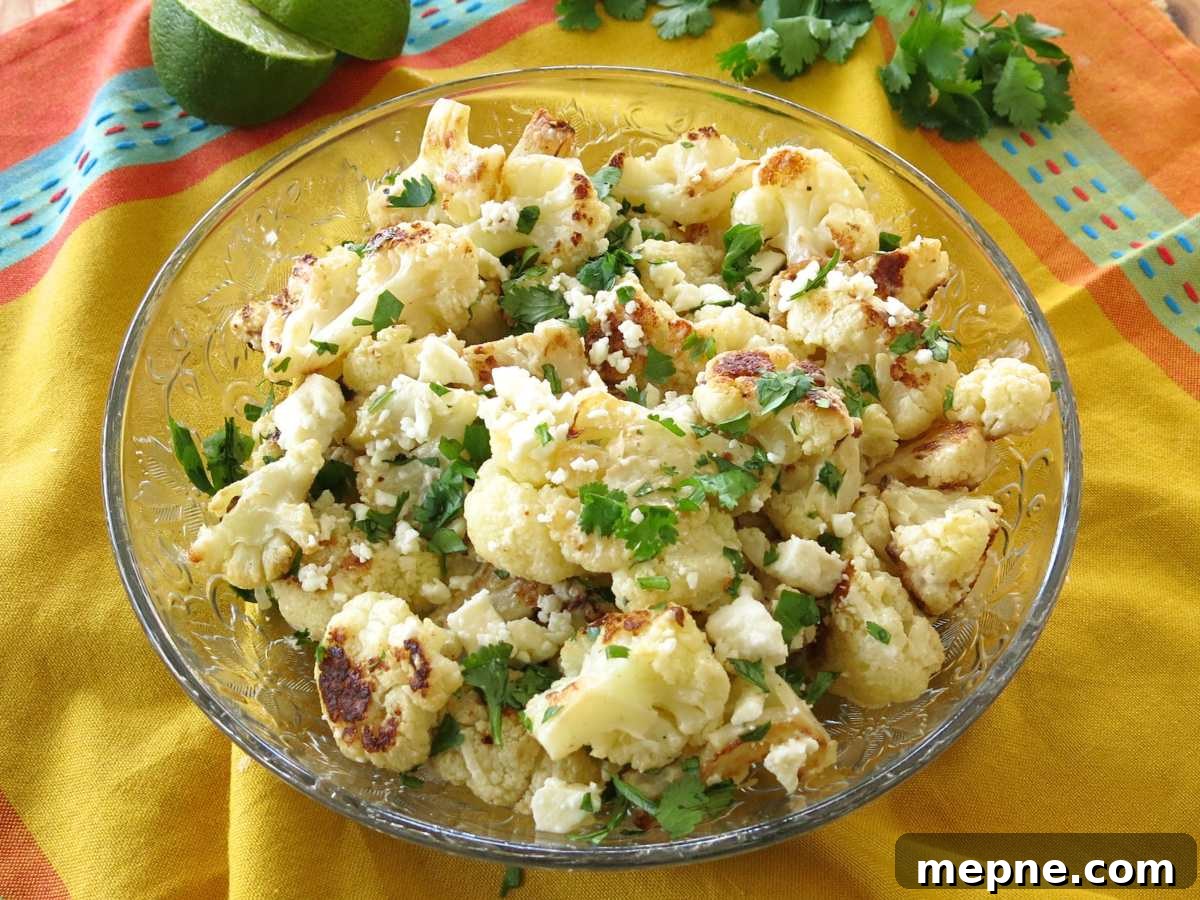 Mexican street style caulifower in a glass dish with limes and cilantro behind it.