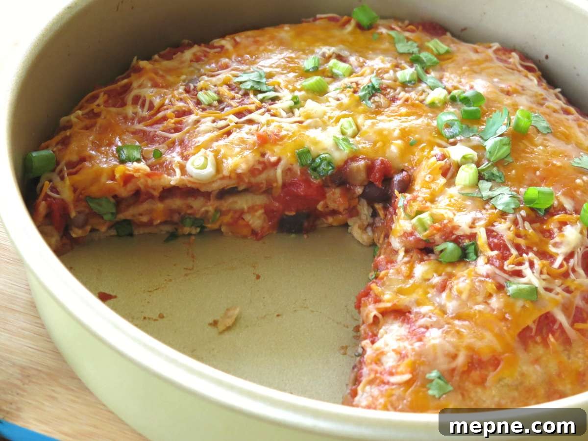 Layered burrito pie in a pan with a slice removed.