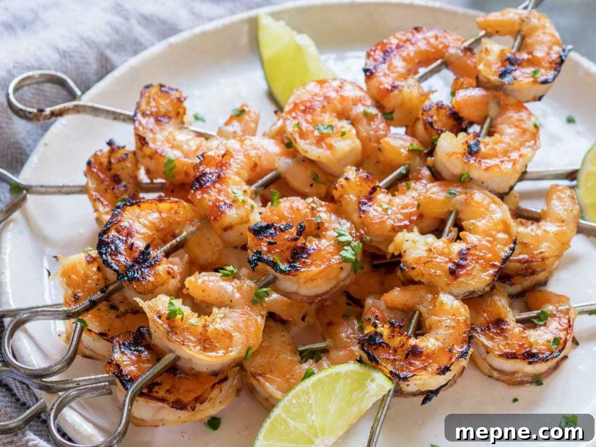 Five skewers of Margarita shrimp on a plate with with lime wedges.