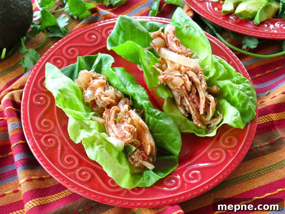 Two chicken tacos in lettuce wraps on a red plate.