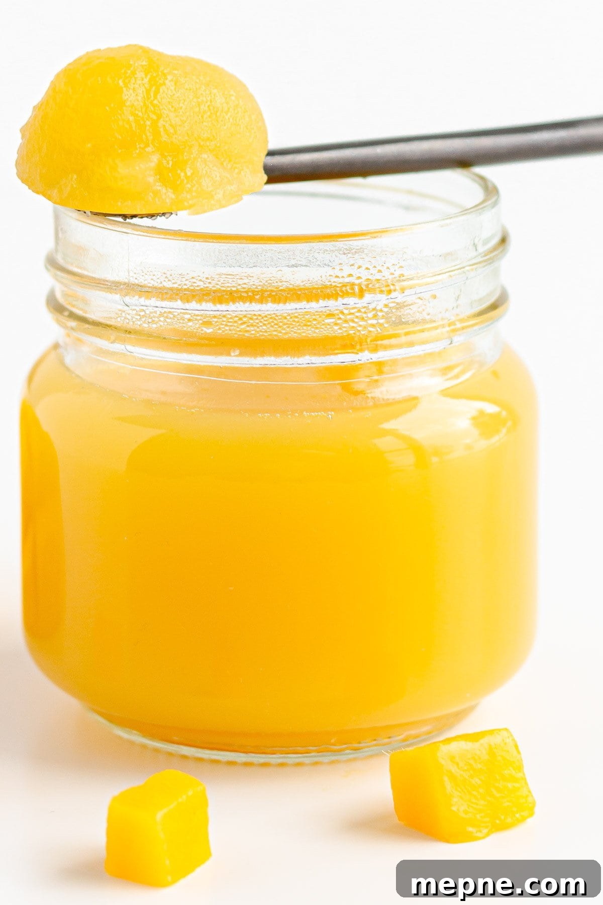 Homemade Mango Jelly Recipe with Fresh Mango 2 Jar of mango jelly with spoonful resting on top.