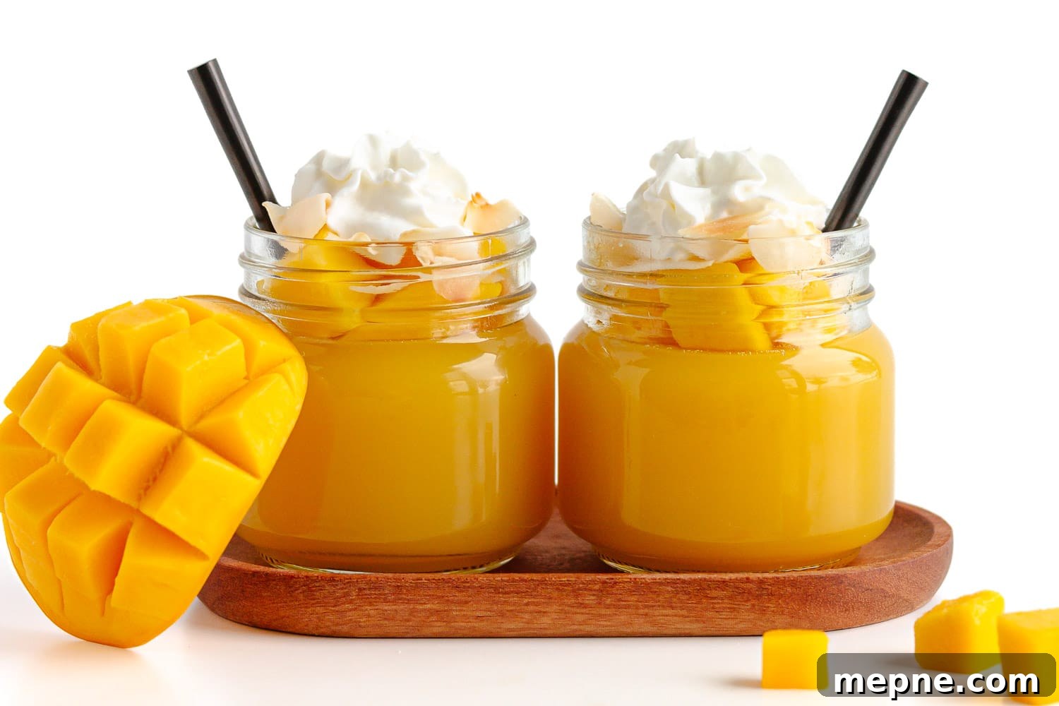 Homemade Mango Jelly Recipe with Fresh Mango 12 Two mango jellies in small glass jars topped with fresh diced mango, toasted coconut flakes and whipped cream.