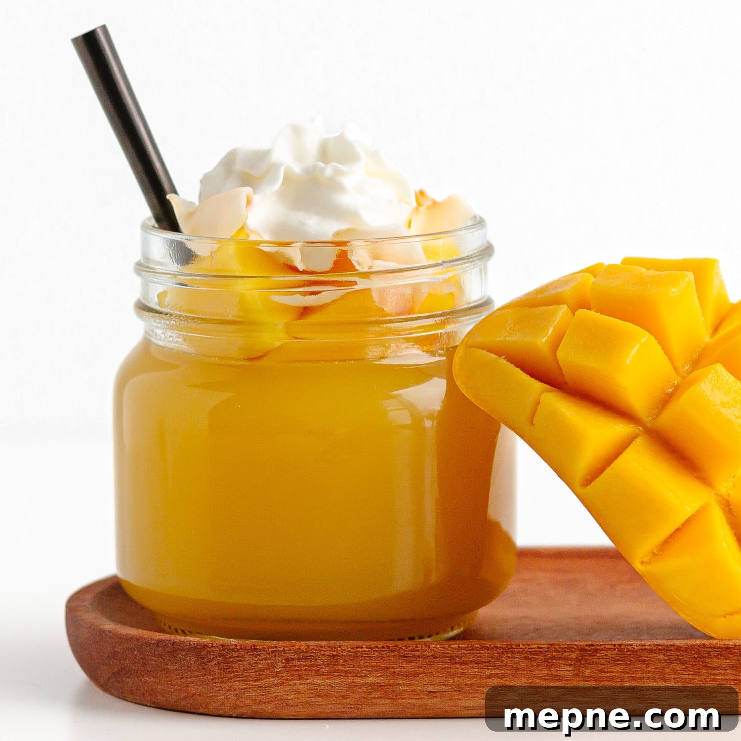 Homemade Mango Jelly Recipe with Fresh Mango 14 Jar of mango jello topped with diced mango, coconut flakes and whipped cream next to half a fresh mango cheek.