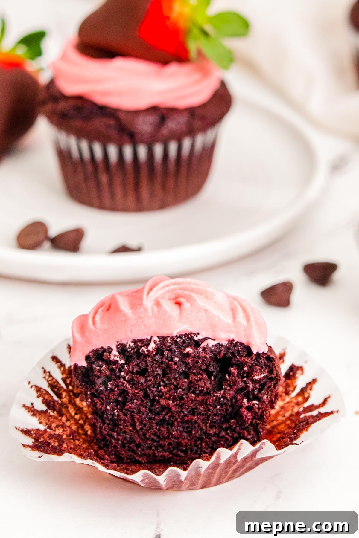 Close up photo of a Strawberry chocolate cupcakes cut in half on a white table.