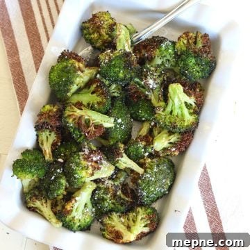Crispy Air Fryer Broccoli Recipe 5 air fryer broccoli served on a white oval platter with a sprinkle of white cheese.