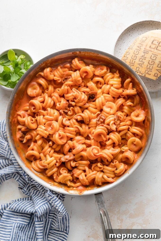 Creamy Sun-Dried Tomato Pasta Recipe 3 Overhead view of a large skillet full of creamy tomato pasta with sun-dried tomatoes mixed in.