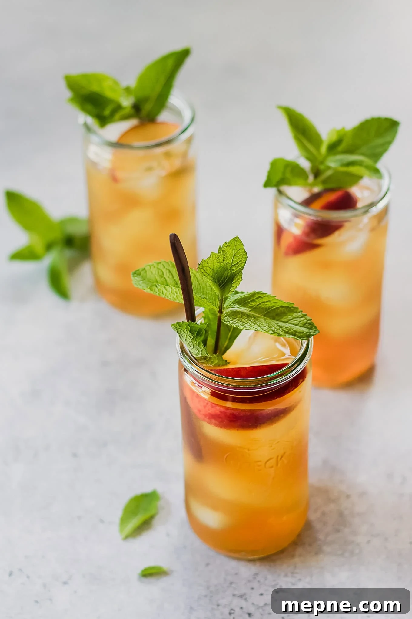 Cold Brew Peach Iced Tea Recipe: Refreshing Summer Drink 3 three jars of peach iced tea with mint sprigs.