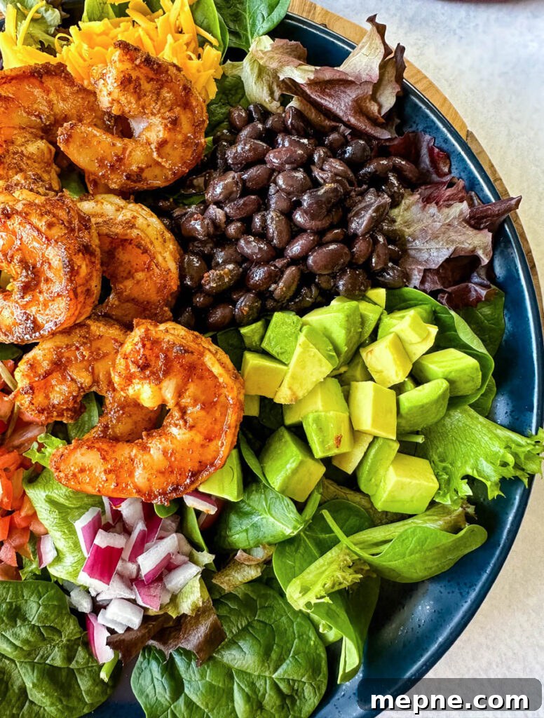 Shrimp Taco Salad with Creamy Lime Dressing 11 shrimp taco salad with avocado, corn, black beans, onions and salsa on a blue plate
