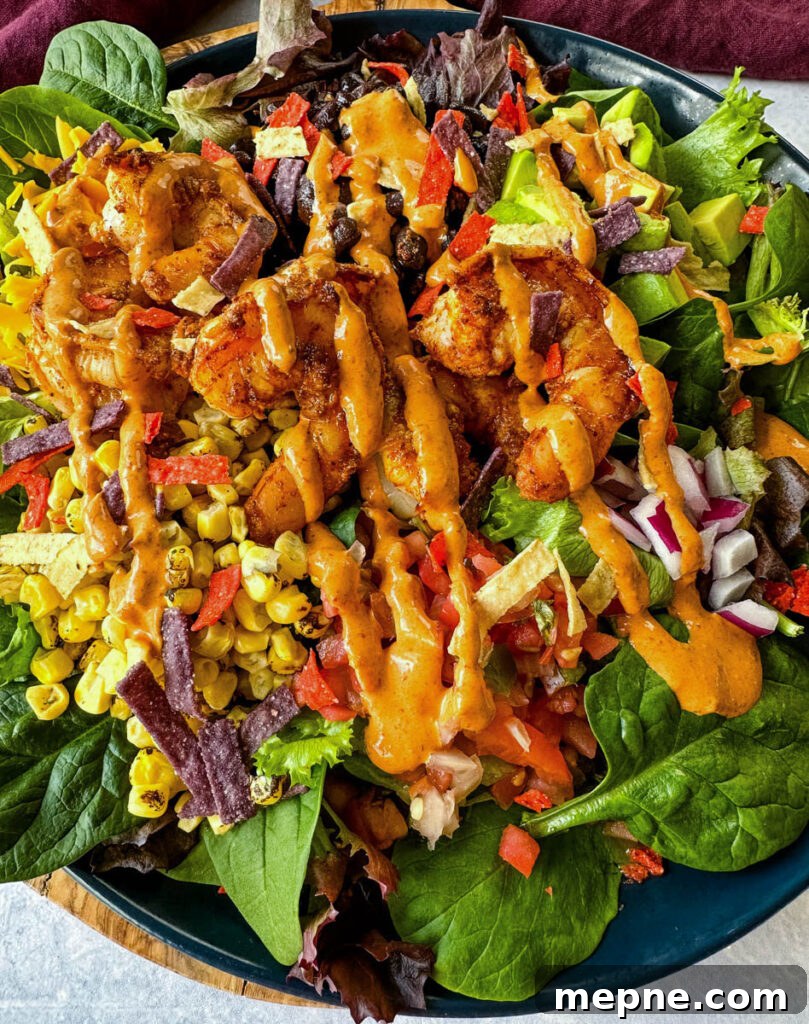 Shrimp Taco Salad with Creamy Lime Dressing 12 shrimp taco salad with avocado, corn, black beans, onions and salsa on a blue plate with Chipotle ranch dressing