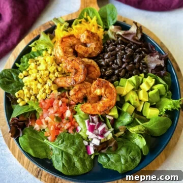 Shrimp Taco Salad with Creamy Lime Dressing 13 shrimp taco salad with avocado, corn, black beans, onions and salsa on a blue plate