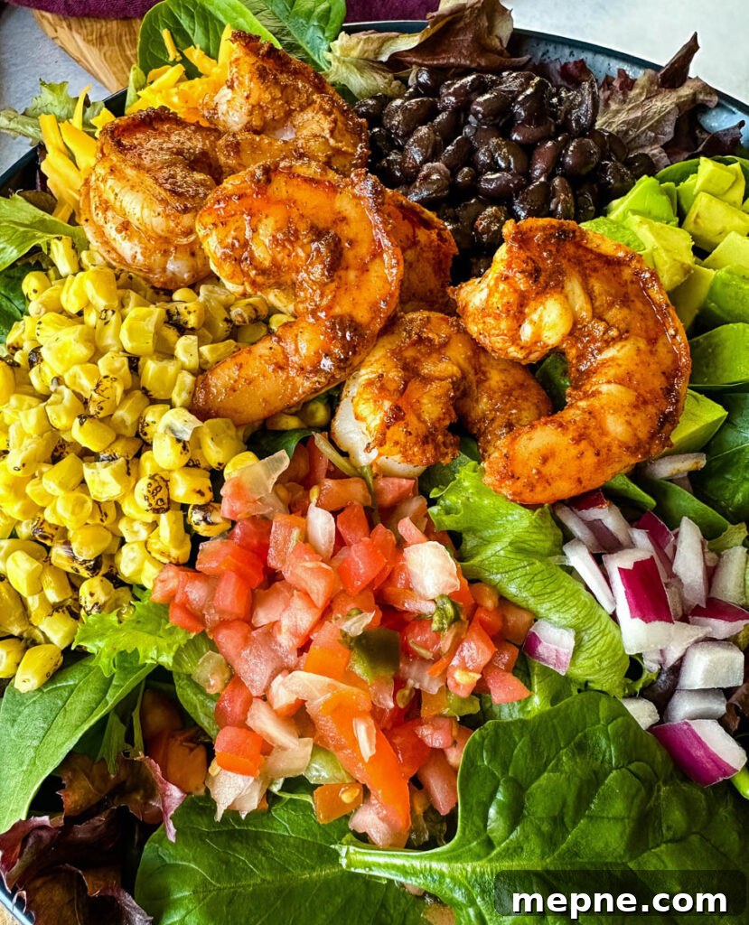 Shrimp Taco Salad with Creamy Lime Dressing 10 shrimp taco salad with avocado, corn, black beans, onions and salsa on a blue plate