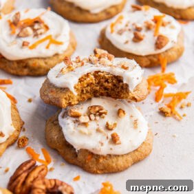 Spiced Carrot Cake Cookies with Cream Cheese Frosting 12 carrot cake cookie with a bite leaning on top of another cookie.