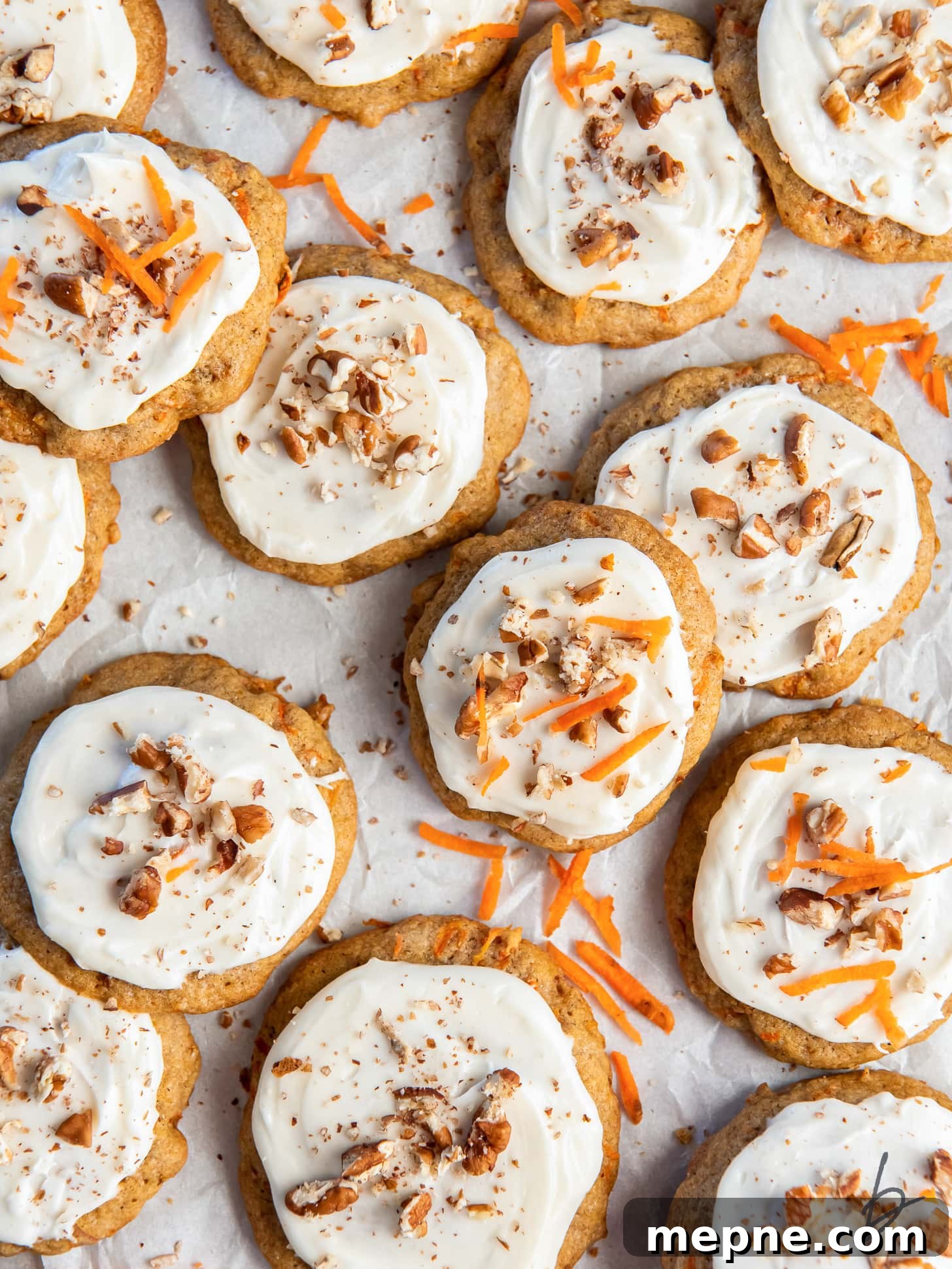 Spiced Carrot Cake Cookies with Cream Cheese Frosting 6 carrot cake cookies with cream cheese frosting garnished with chopped walnuts and carrot shreds.